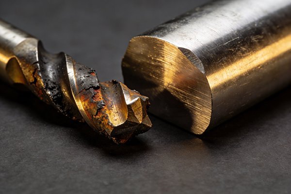 A broken carbide end mill next to a machined part