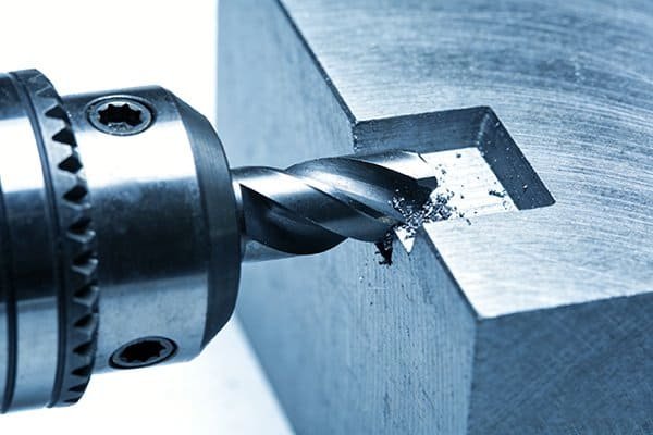 A face mill with indexable inserts machining a large metal block.