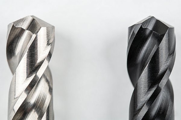 A shiny uncoated end mill next to a dark TiAlN coated end mill